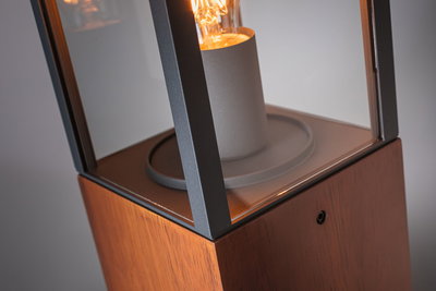 Close-up van moderne vloerlamp met houten voet en zwart metalen frame voor LED-lamp.