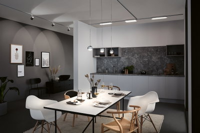 Salle à manger moderne avec table blanche, chaises en bois et plastique, crédence grise et suspensions LED