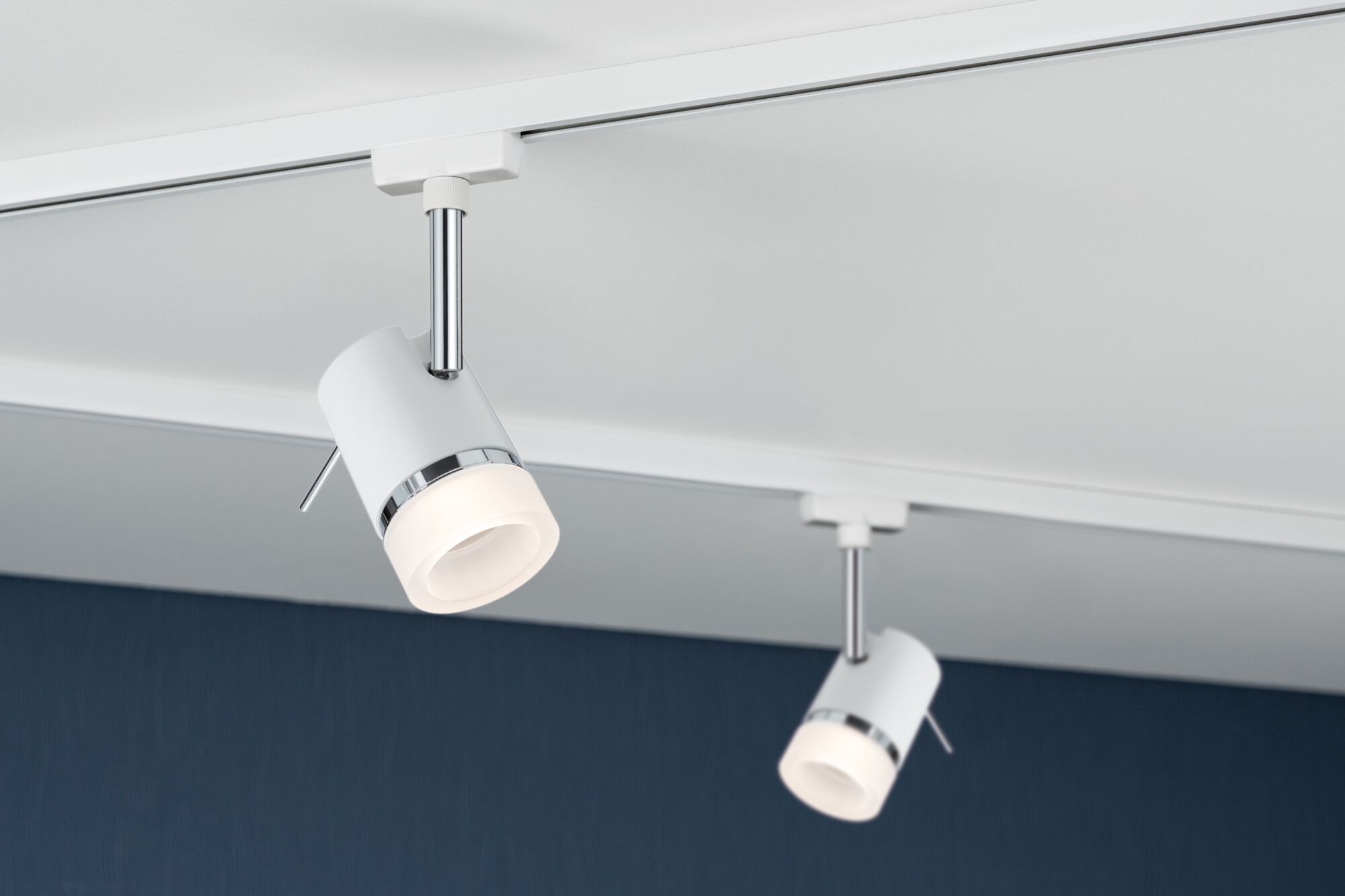 Moderner weißer LED-Strahler aus Metall mit Chromakzenten an Schienensystem für Wohnraumbeleuchtung