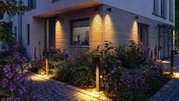Moderne Außenbeleuchtung mit warmweißen LED-Wandleuchten und Pollerleuchten an Hausfassade und Gartenweg
