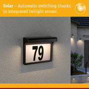 Black solar house number sign with integrated twilight sensor lighting on grey wall
