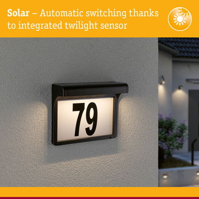 Solar-powered house number 79 with integrated twilight sensor and black frame mounted on grey wall