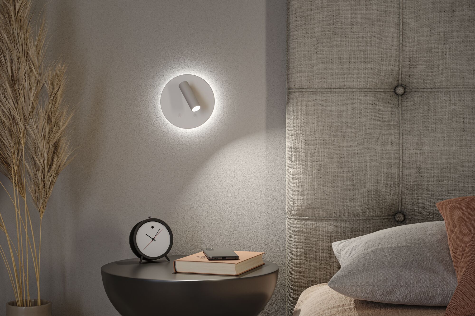 Moderner weißer LED-Wandleuchter mit Leselicht über Nachttisch mit Buch und Wecker im Schlafzimmer