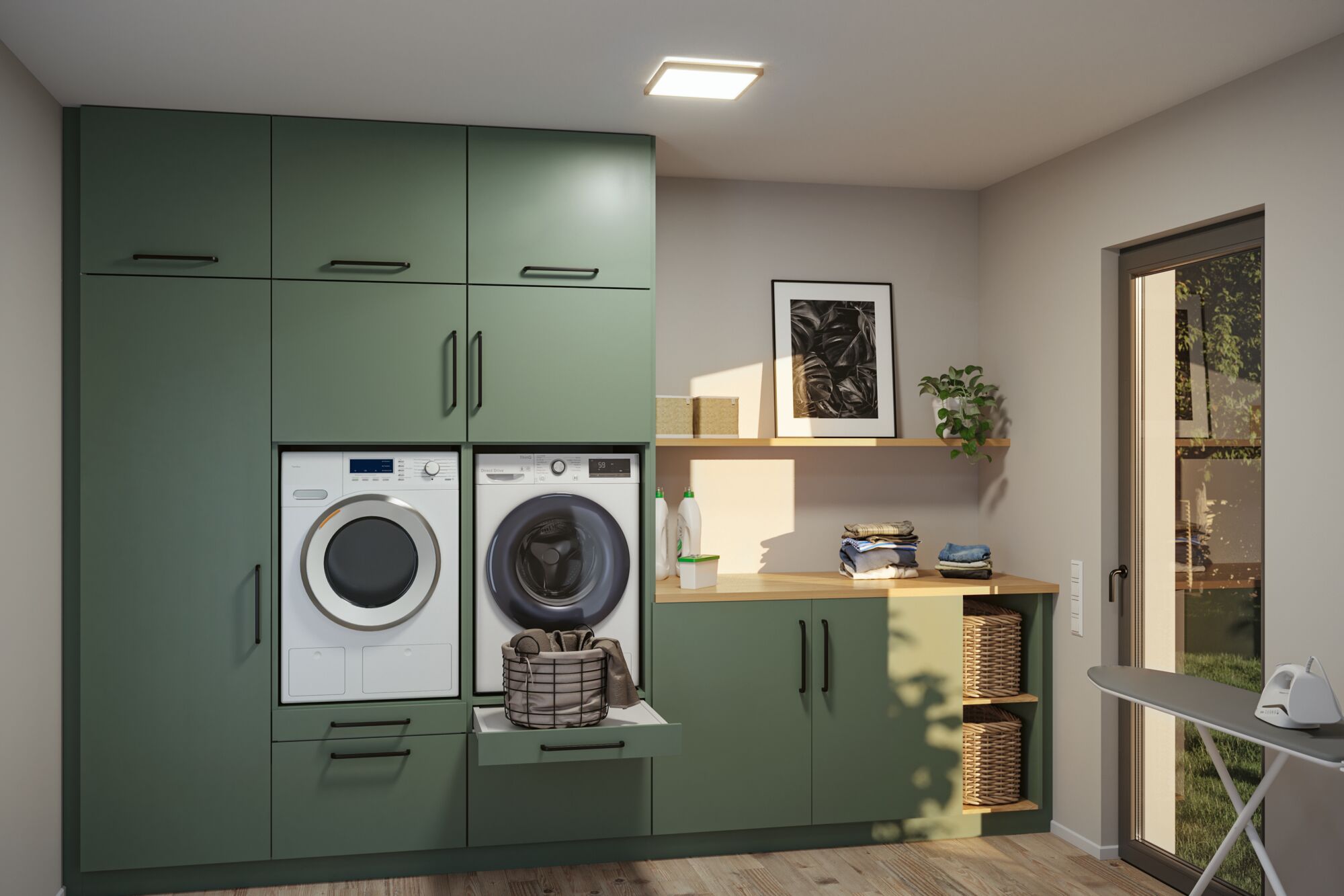 Modern laundry room with green wooden cabinets, washing machine, dryer, and ironing board by the window.