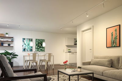 Salon moderne avec canapé beige, plantes, table à manger blanche et éclairage LED au plafond.