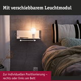 Weißes Wandregal mit verschiebbarem Leuchtmodul und warmweißem Licht neben Bett mit Kissen und Decke