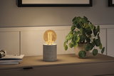 Moderne bordlampe med grå betonfod og varmt hvidt LED-pæreslys på skænk.
