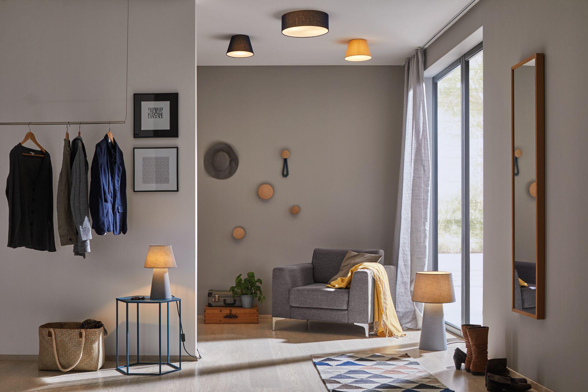Modernes Wohnzimmer mit grauem Sessel, gelber Decke und zwei grauen Tischlampen für Wohnraumbeleuchtung