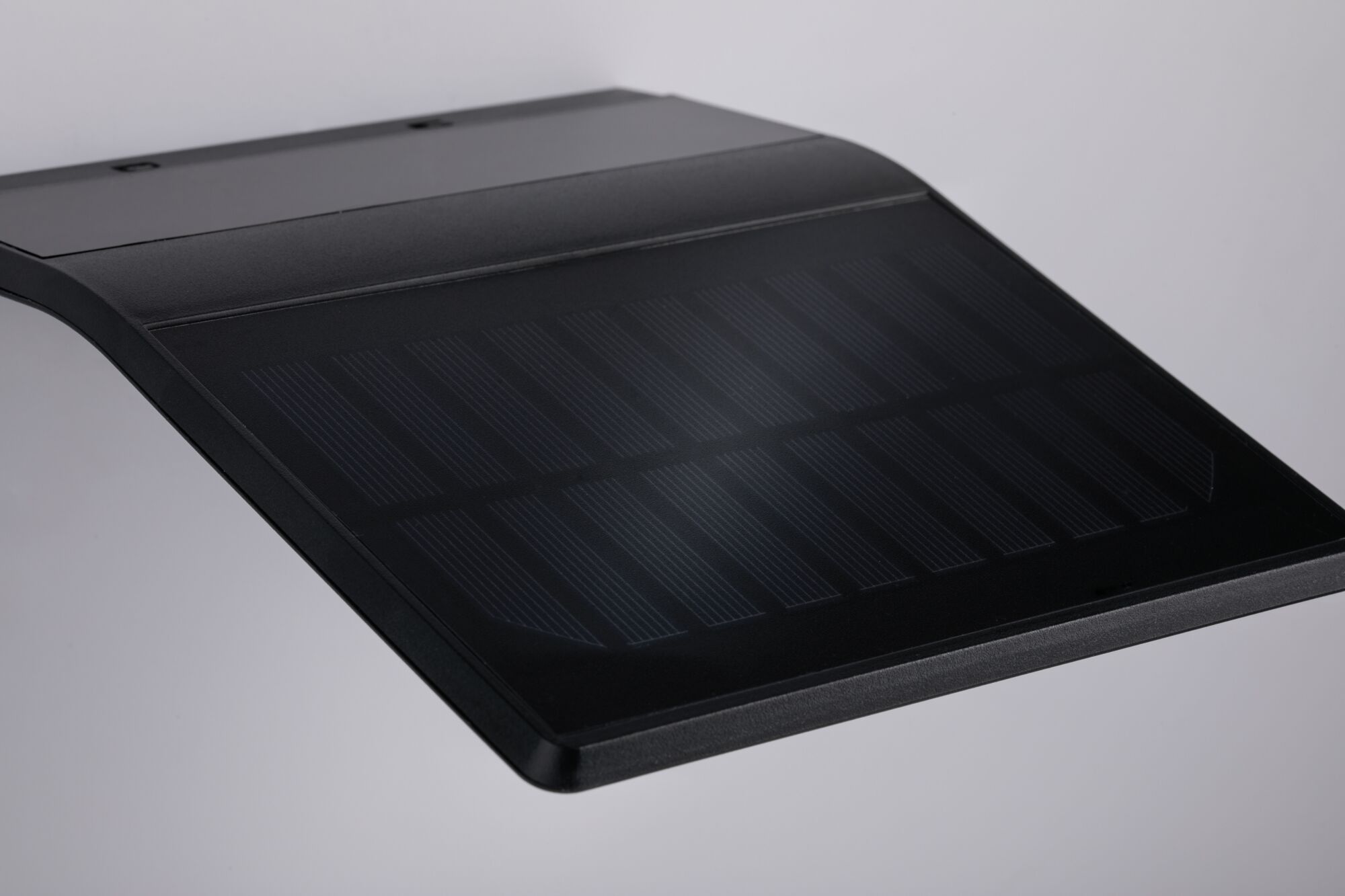Schwarzes, gebogenes Solarpanel mit feinen Linien auf glatter Oberfläche für nachhaltige Energie.