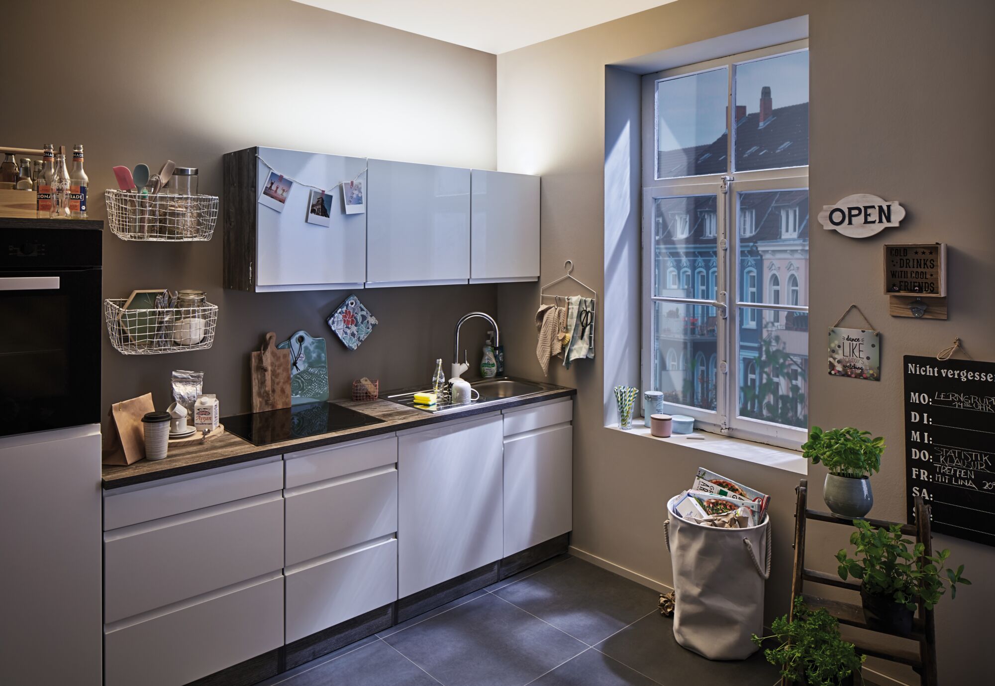 Cuisine moderne avec façades blanches, plan de travail en bois, grande fenêtre et éclairage de cuisine élégant