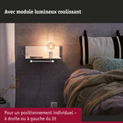 Support mural blanc avec ampoule sur mur gris à côté d'un lit avec couverture tricotée et coussin