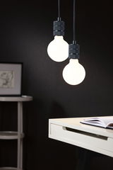 Two hanging LED bulbs with black holders above white desk in modern interior setting