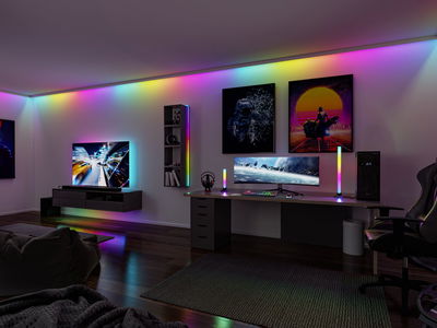 Modern gaming room with RGB LED lighting on wall, desk, and TV creating ambient colorful light effects.