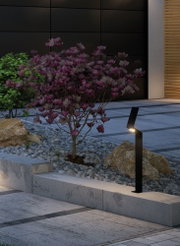 Projecteur extérieur LED noir moderne en métal éclairant un chemin de jardin avec un buisson de magnolia en fleurs