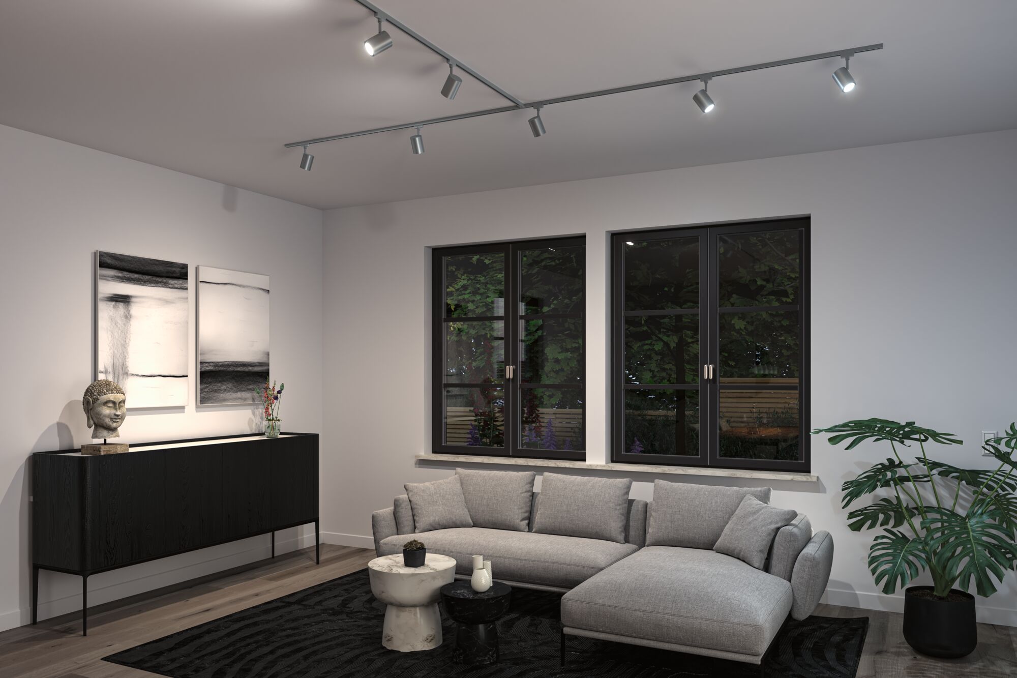 Moderne woonkamer met grijze stoffen bank, zwarte dressoir en verstelbare metalen plafondspots.
