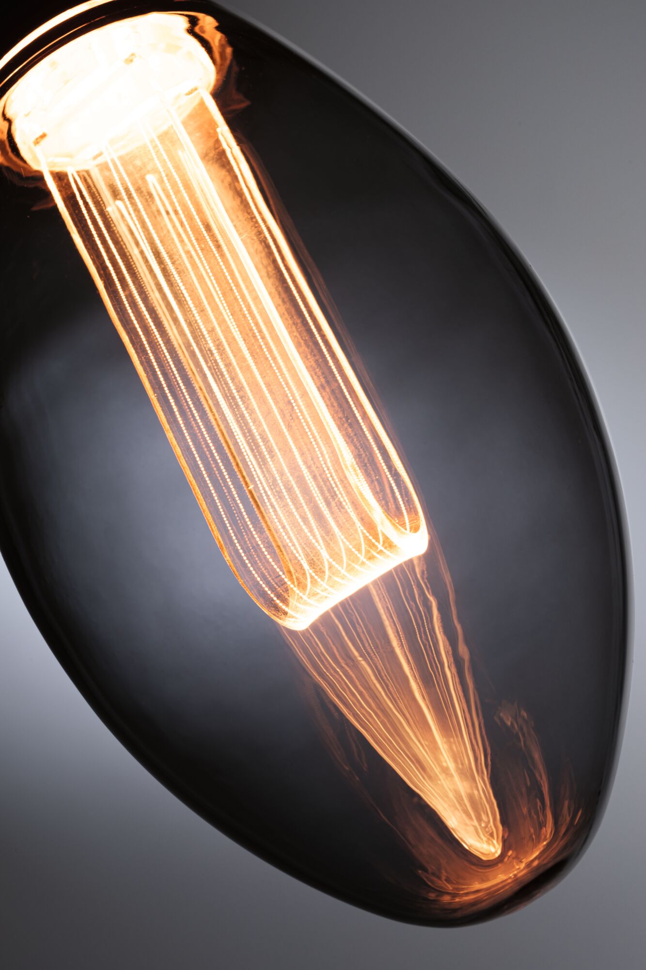 Close-up of a warm glowing filament bulb with elongated glass envelope for decorative lighting