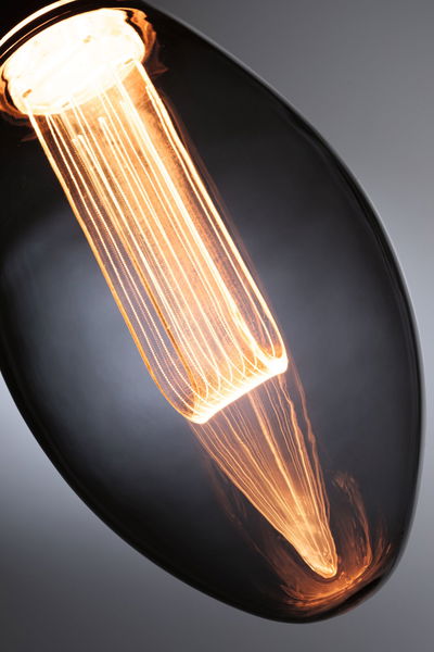 Close-up of a warm glowing filament bulb with elongated glass envelope for decorative lighting