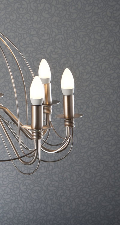 Modern brushed metal ceiling light with three warm white LED candle bulbs against patterned wall