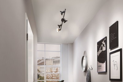 Schwarze Deckenleuchte mit vier verstellbaren Spots in modernem Flur mit Spiegel und Wandbildern.
