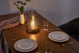 Cozy dining setup with brown glass lamp on wood table, white porcelain with gold rim and gold cutlery