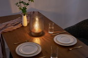 Brown glass table lamp with wooden base on set wooden table with white porcelain and cutlery