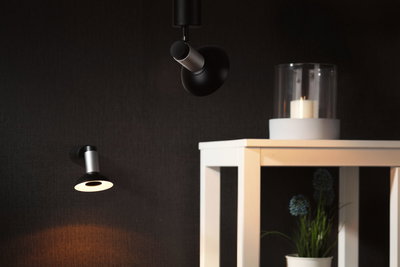 Black and silver LED wall and ceiling lights on dark wall with white table and candle decor