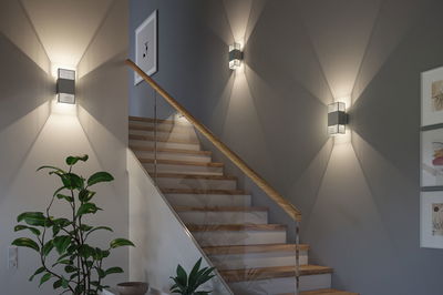 Modern grey metal wall light with decorative light pattern on staircase wall for indoor lighting