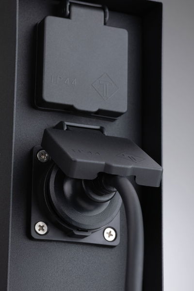 Prise noire IP44 avec couvercle de protection et câble connecté en plastique robuste pour usage extérieur.