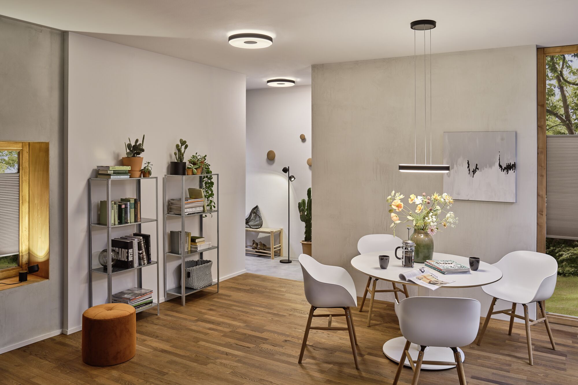 Moderne spisestue med hvidt bord, stole i plastik og træ, LED-loftslamper og pendel.