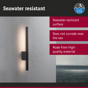 Black wall light with seawater-resistant surface mounted on grey wall overlooking the sea