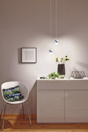 Moderne weiße Hochglanz-Kommode mit Deko und zwei runden LED-Hängeleuchten in warmweißem Licht