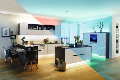 Modern white kitchen island with black countertop and LED lighting on light wooden floor