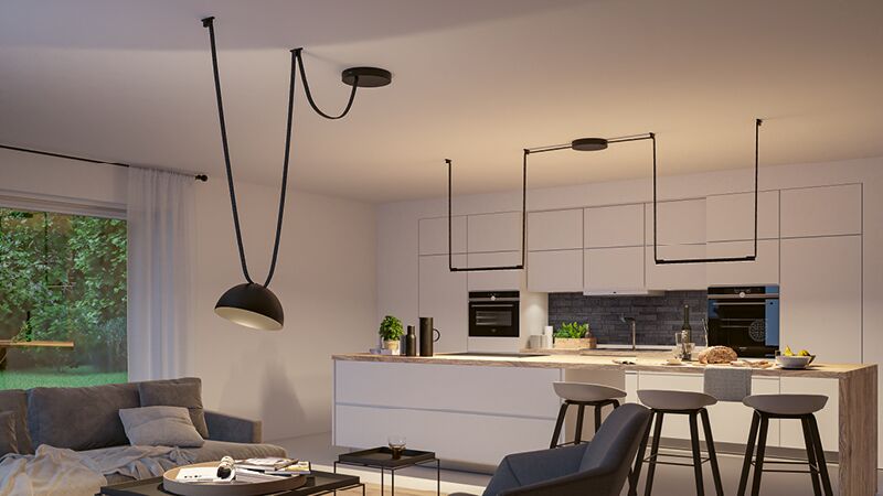 Moderne offene Küche mit weißer Insel, schwarzen Barhockern und minimalistisches schwarzen Gurtsystem als Beleuchtung