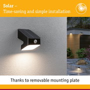 Black solar outdoor wall light with motion sensor mounted on grey wall, energy-saving LED lighting