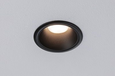 Black metal recessed spotlight with warm white LED light in white ceiling for modern lighting design
