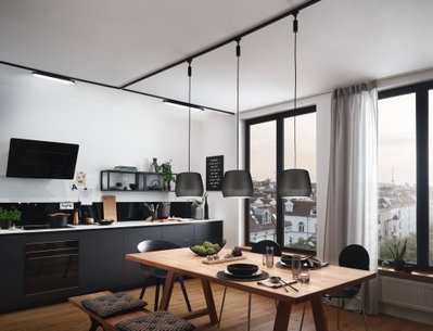 Moderne Küche mit schwarzen Hängelampen aus Metall über Holztisch, große Fenster und Stadtblick