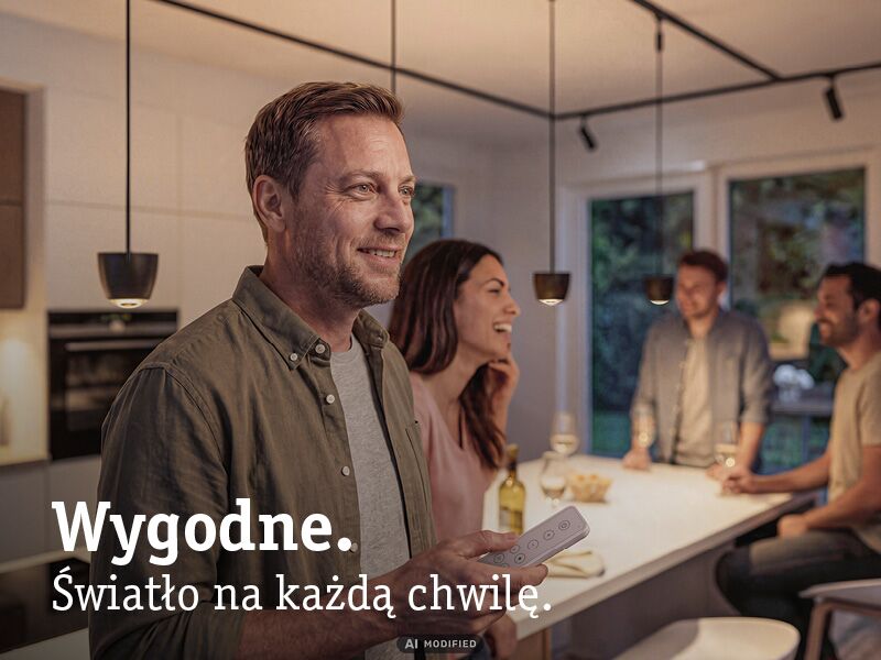 Mężczyzna steruje nowoczesnymi czarnymi lampami wiszącymi w przytulnej kuchni z przyjaciółmi.