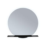 Round wall mirror with black shelf and LED lighting for modern bathroom design.