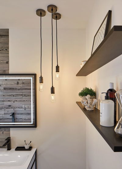 Three black pendant lights with Edison bulbs in modern bathroom featuring wood-effect mirror.