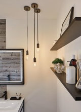 Drie zwarte hanglampen met Edison-lampen in moderne badkamer met spiegel in houtlook.