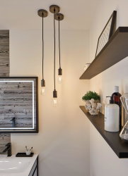 Three black pendant lights with exposed bulbs in modern bathroom featuring wood decor and shelves.