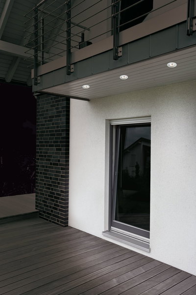 Trois spots LED encastrés blancs sous un auvent moderne avec terrasse en bois grise et fenêtre.