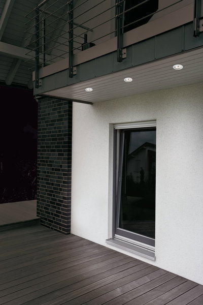 Drei weiße LED-Einbaustrahler in moderner Hausüberdachung mit grauer Holzterrasse und Fenster.