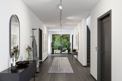 Modern hallway with grey flooring, white walls, black sideboard and ceiling spotlights for living space lighting