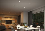 Moderne woonkamer met witte ingebouwde LED-plafondlampen en gezellige inrichting met open haard.