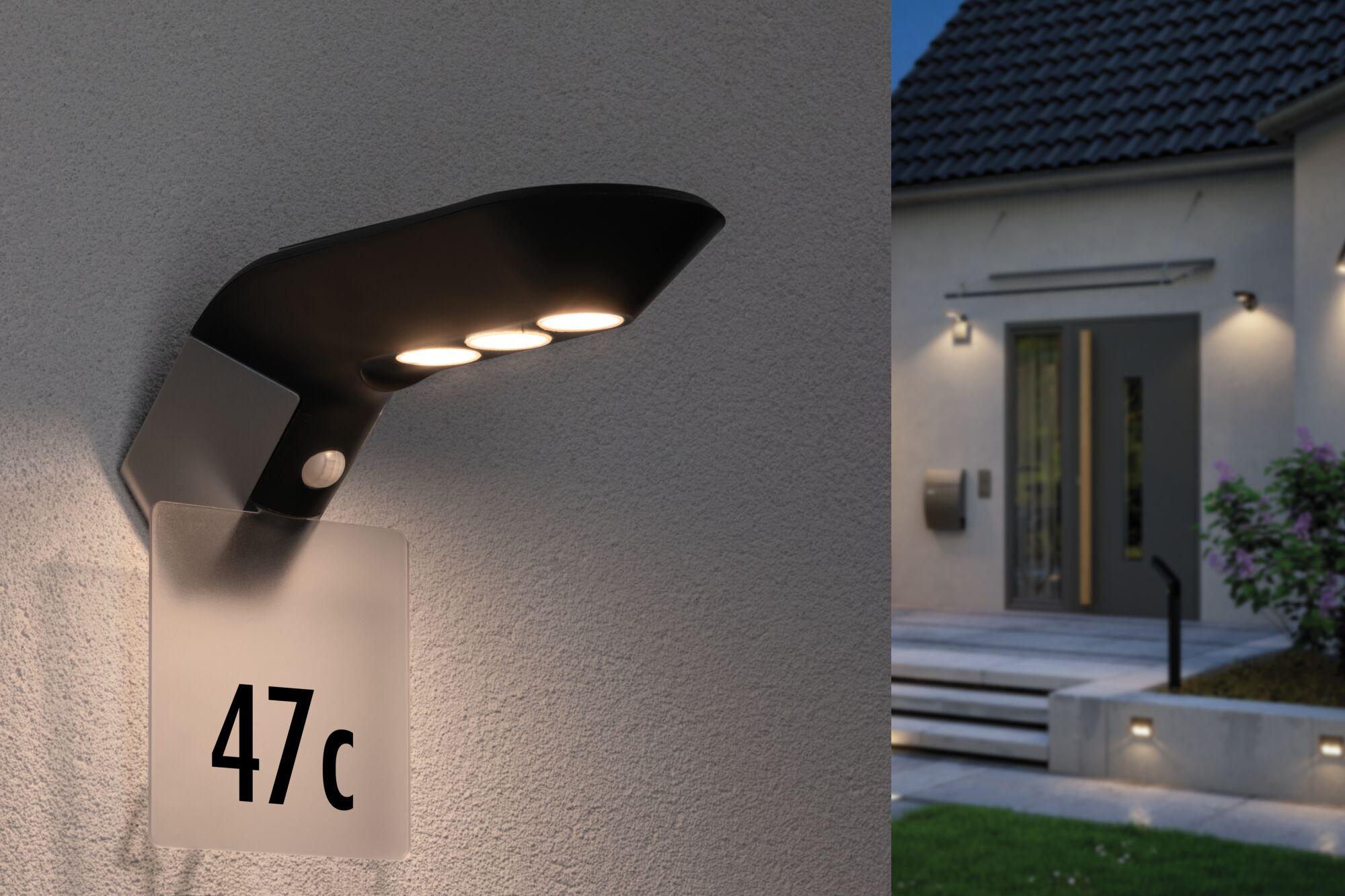 Modern black LED outdoor wall light with motion sensor and house number plate on grey wall