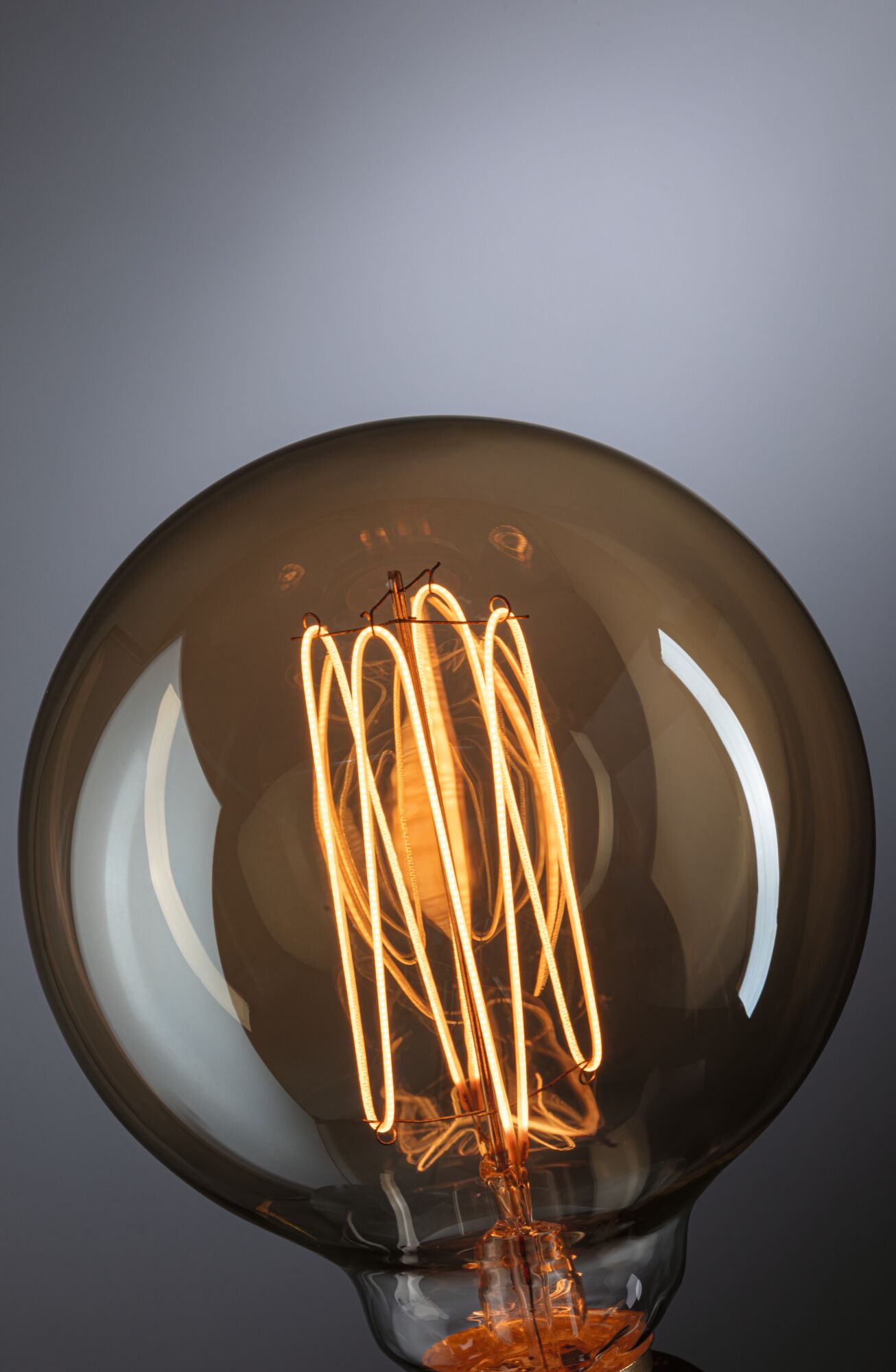 Nahaufnahme einer warm leuchtenden Glühbirne mit sichtbarem Filament und braunem Glas für dekorative Beleuchtung