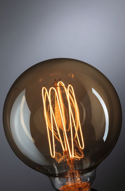 Close-up of warm glowing light bulb with visible filament and brown glass for decorative lighting