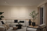 Moderne woonkamer met beige bank, zwarte accenten en minimalistische plafondverlichting voor een gezellige sfeer