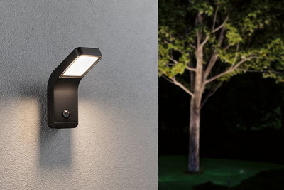 Sort LED-udendørsvæglampe med bevægelsessensor på grå væg oplyser have om natten